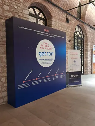 Getron tanıtım fonu — Kurumsal tanıtım için kurulan geniş backdrop; yanında ayrı bir roll-up uygulaması yer alıyor.